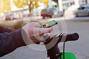 Man on an electric scooter is ordering food on the internet using an app outside