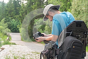 Man on electric wheelchair using mirrorless camera nature, enjoying freedom and doing art