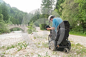 Man on electric wheelchair using mirrorless camera nature, enjoying freedom and doing art