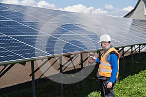 Man with electric wrench tightens the bolts securing solar panels to a metal base.