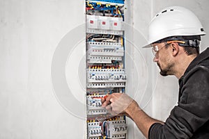 Man, an electrical technician working in a switchboard with fuses. Installation and connection of electrical equipment