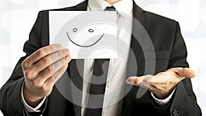 Man in elegant business suit holding up a white card with smiley