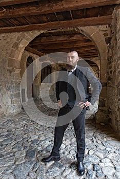 Man in elegant clothes poses under the arcades