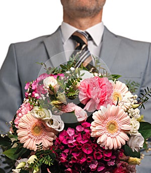 Man in an elegant suit hands over a colorful bouquet of flowers