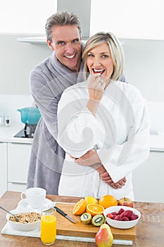 Man embracing a happy woman from behind in kitchen