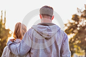 Man embracing her girlfriend after work out in park with lens flare