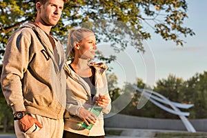 Man embracing her girlfriend after work out in park with lens flare