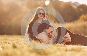 Man embracing his wife. Woman is pregnant. Lovely couple sitting on the field together