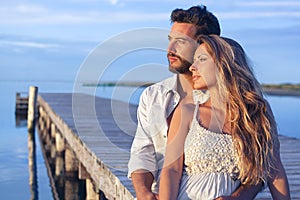 Man embracing his woman from behind on seaside background under