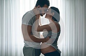 Man embracing and kissing pregnant