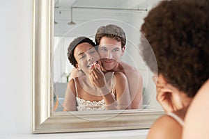Man Embracing Woman Applying Lipstick In Mirror
