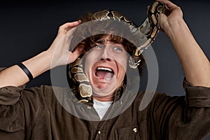 man emotionally screams, with snake on his head