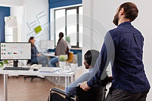 Man employee helping his invalid african colleague coming in workplace