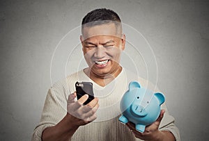 Man employee holding piggy bank looking at smart phone