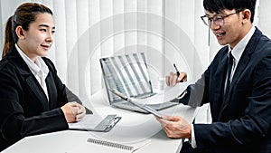 Man employer holding resume of applicant and reading her profile during asking candidate question and explaining