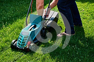 Man empties the lawnmower on a green meadow photo