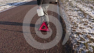 Man with empty can near warning triangle on the road