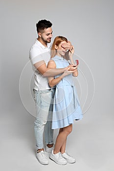 Man with engagement ring making marriage proposal to girlfriend on grey background