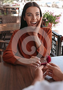 Man with engagement ring making proposal to his girlfriend in outdoor cafe