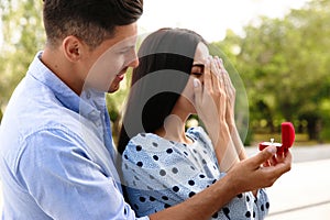 Man with engagement ring making proposal to his girlfriend outdoors