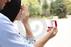 Man with engagement ring making proposal to his girlfriend outdoors, closeup