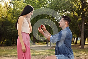 Man with engagement ring making proposal to his girlfriend in park