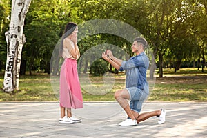 Man with engagement ring making proposal to his girlfriend in park