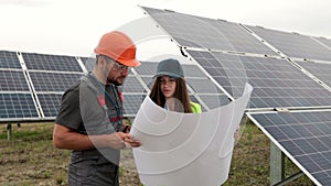 Man engineer in hard hat and inspector engineer woman learning the paper plan construction of solar panels. Alternative