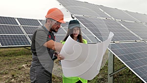 Man engineer in hard hat and inspector engineer woman learning the paper plan construction of solar panels. Alternative