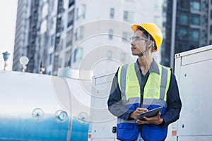 Man engineer holding tablet working at rooftop building construction. Male technician worker working checking hvac of office