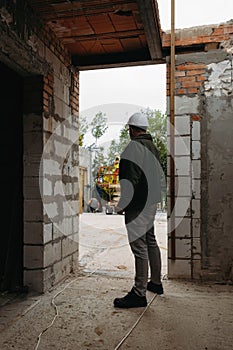 Man engineer standing on construction site looking on workers