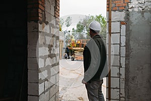 Man engineer standing on construction site looking on workers