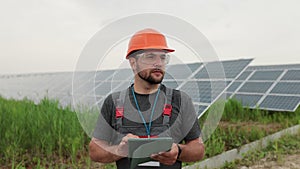 Man engineer in uniform hold digital tablet and working near solar panels power farm. Solar panel field. Clean energy