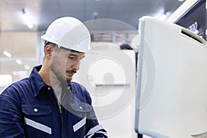 Man engineer using computer controlling cnc machine at workshop. professional male control automated machine process programming