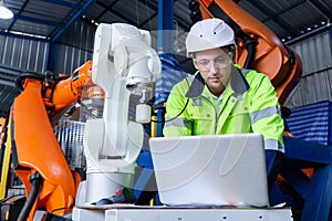 man engineer using laptop control robot arm automate. robotic automation in line production at industrial. Test performance of