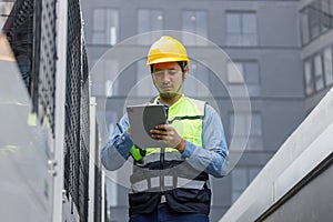 Man engineer using tablet working at rooftop building construction. Male technician worker working checking HVAC of office
