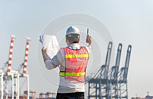 The man engineer working with container Cargo freight ship in shipyard at dusk