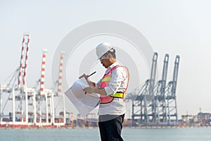 The man engineer working with container Cargo freight ship in shipyard at dusk