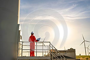 Man engineer working and holding the laptop for check performance of wind turbine farm Power Generator Station, Concept of