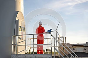 Man engineer working and holding the laptop for check performance of wind turbine farm Power Generator Station, Concept of