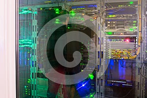 The man engineer works in the server room of a modern data center. Multiple network servers