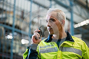 Man engineering wearing safety hard hat using radio walkie talkie talking to team to work in factory. heavy industry production