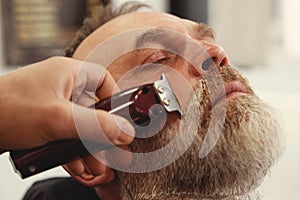 man enjoing haircut by a master in a barbershop. An old man gets a stylish haircut