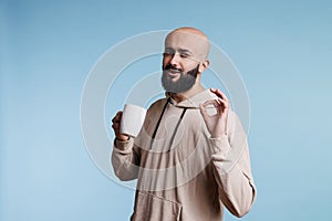 Man enjoying coffee, showing ok gesture