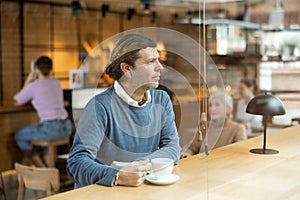 Man enjoying cup of coffee at table in cozy cafe