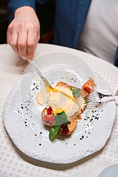 Man cutting freshly cooked poached egg with knife