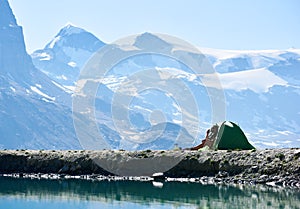 Man enjoying mountains scenery near tent.