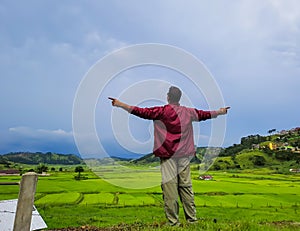 man enjoying natural green paddy field with dramatic sky view at evening from flat angle