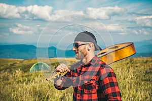 Man enjoying nature. Handsome traveler with guitar in autumn mountain.