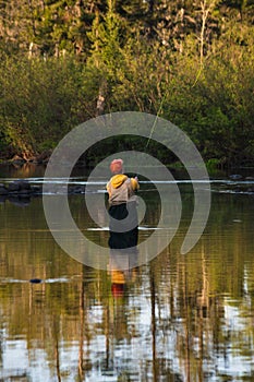 Man is enjoying a peaceful afternoon of fishing in a tranquil river surrounded by lush vegetation